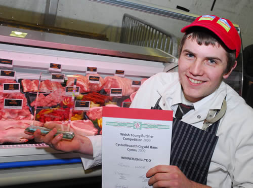 Tomos Hopkin proudly shows off the Welsh Young Butcher of the Year trophy and his display of pork.