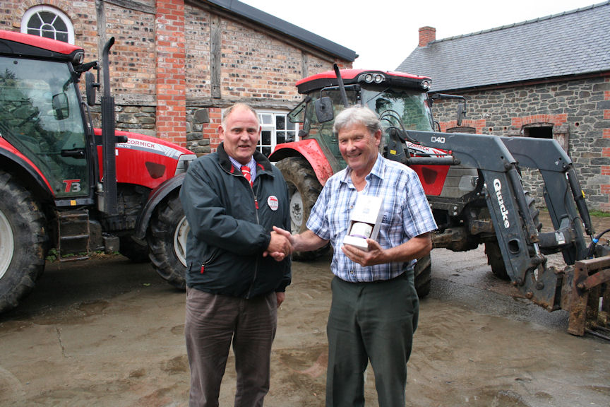 Merfyn Edwards (right) receives a celebratory bottle of whisky from Terry Hughes, managing director of HJR Agri (Oswestry) Ltd, after purchasing the 100th McCormick tractor supplied by the dealership.