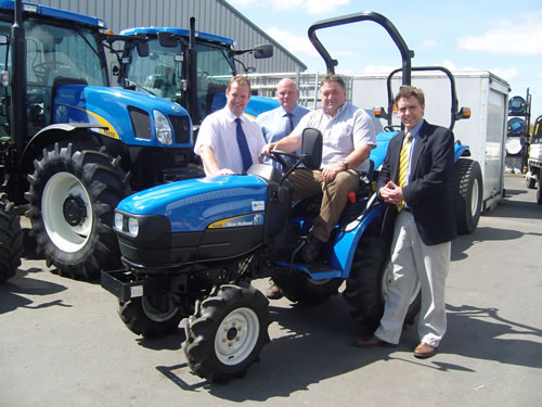 Alex Burgess tries the tractor for size, with (left to right) Brent Gibbon of Dow AgroSciences, dealership manager Steve Mitchell, and Andrew Barbour of New Holland